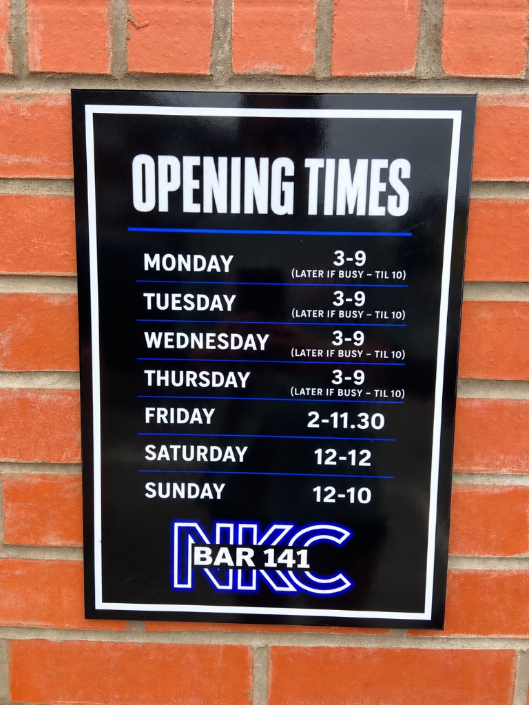 Official NKC Bar 141 Opening Times Plaque on the brick wall